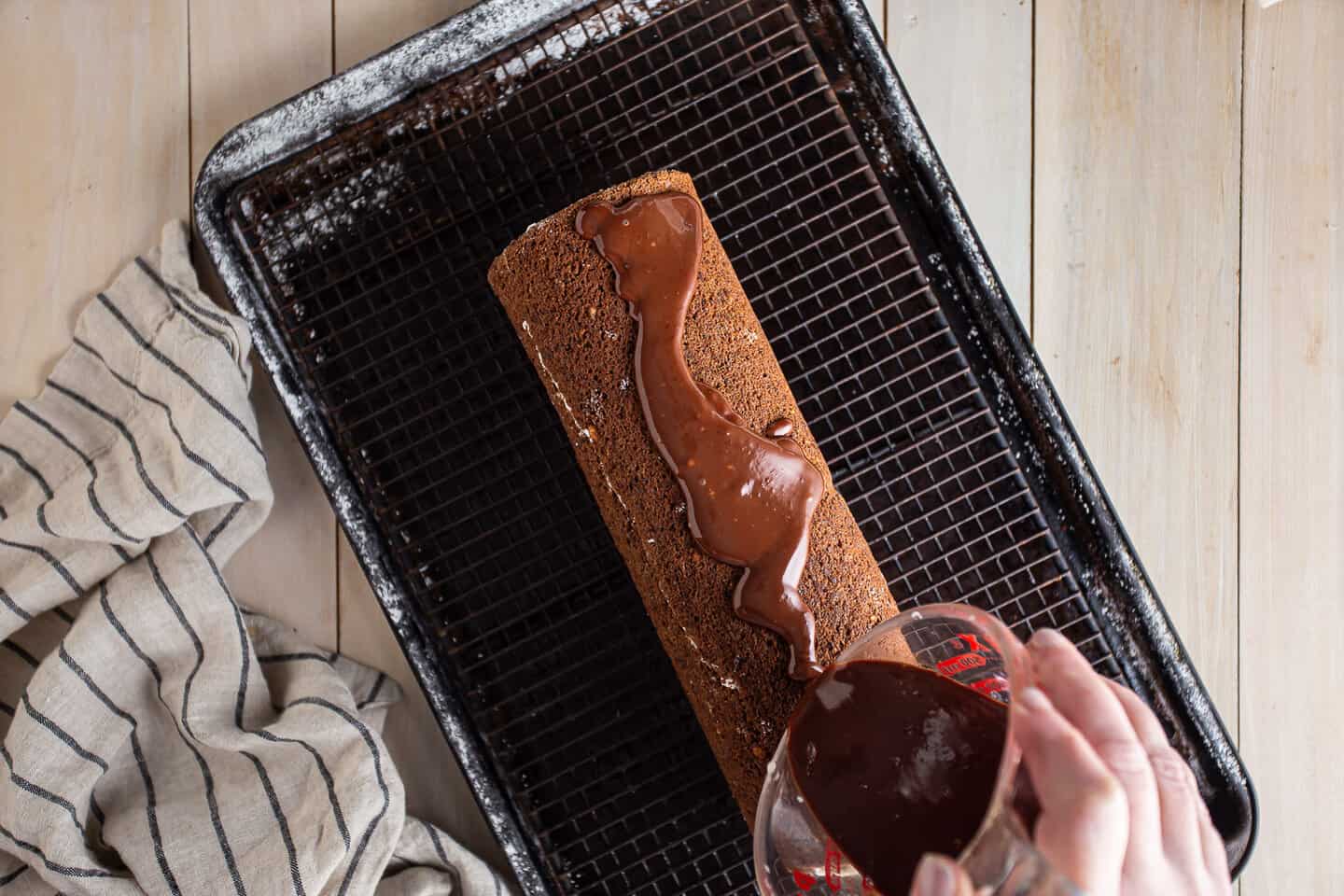Pouring chocolate glaze over Swiss cake roll.