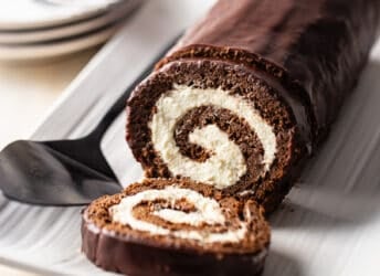 Swiss roll cake sliced and presented on a white serving platter.