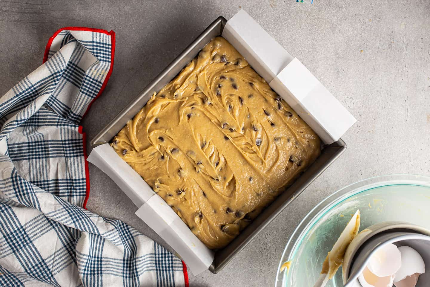 Unbaked chocolate chip blondies in a square baking pan.