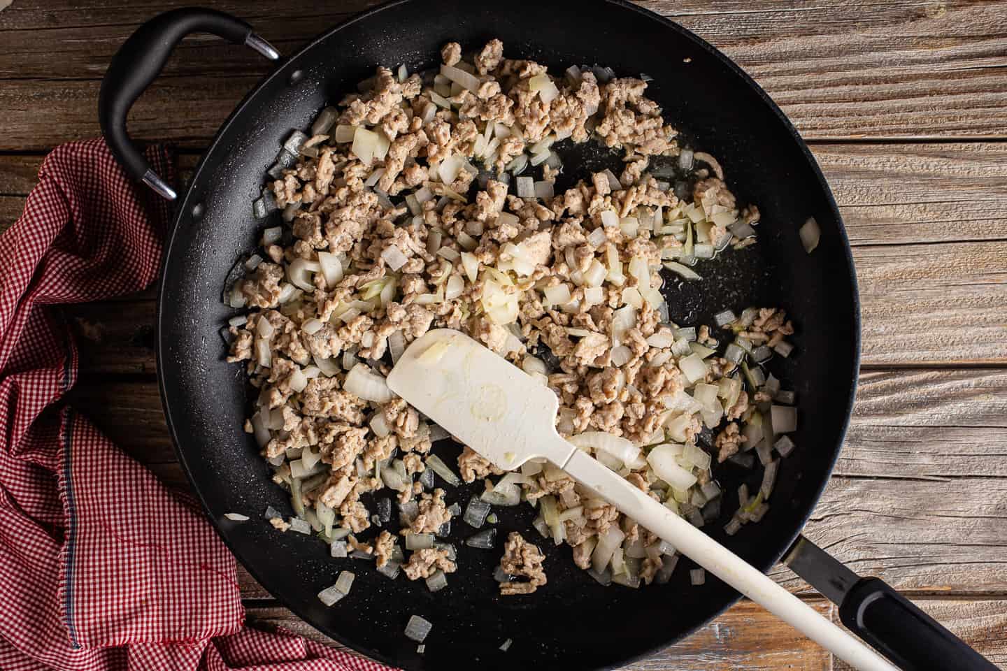 Cooking ground chicken and onions together in a large black skillet.