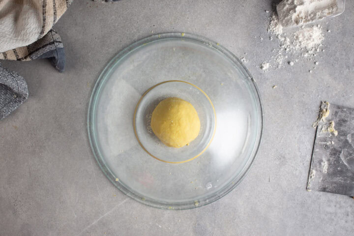 Fresh pasta dough resting under a glass bowl.