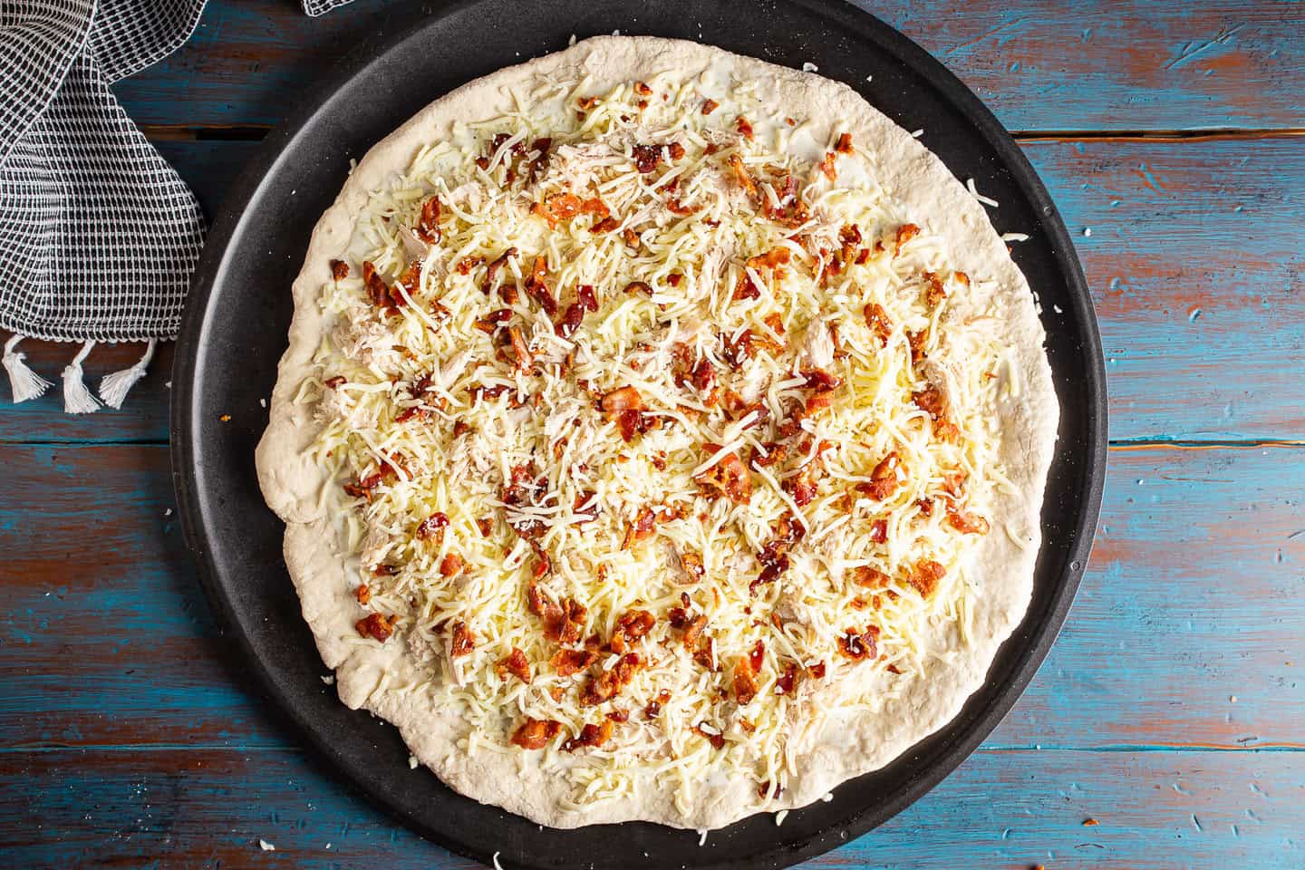 Unbaked homemade chicken bacon ranch pizza.