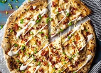 Chicken bacon ranch pizza cut into slices and presented on a blue background.
