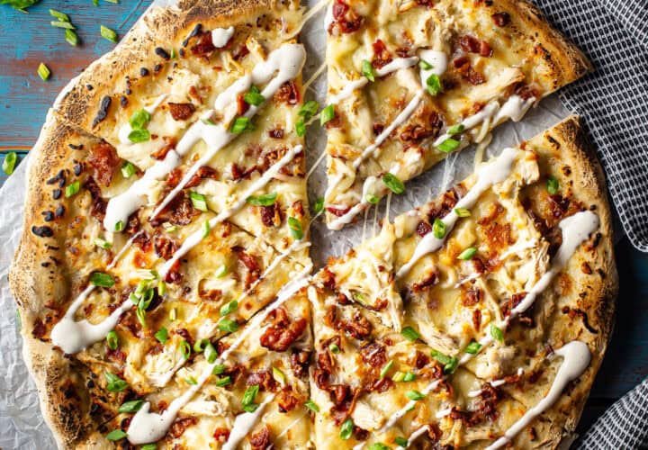Chicken bacon ranch pizza cut into slices and presented on a blue background.
