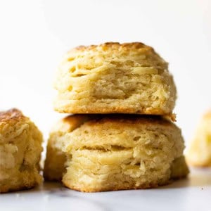 two buttermilk biscuits stacked on a white table.