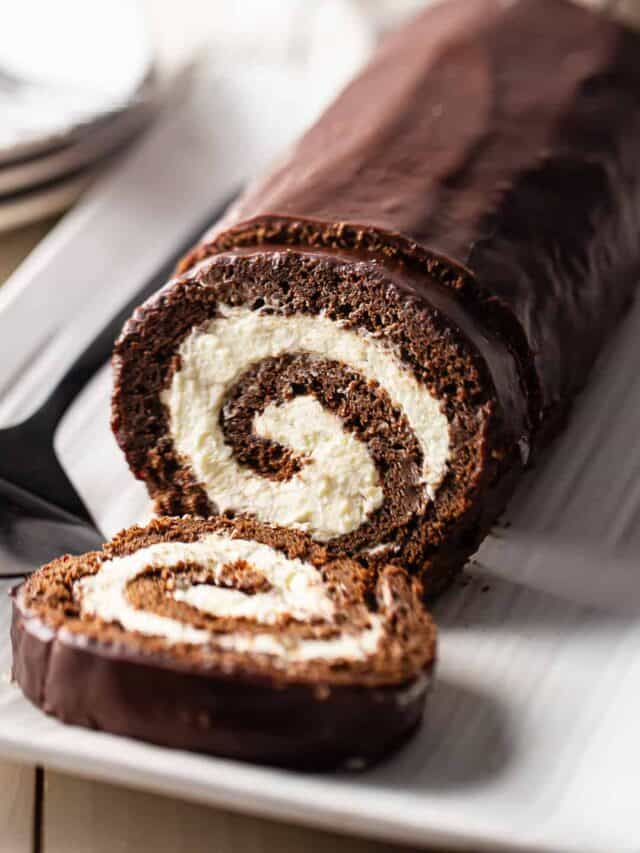 Swiss roll cake sliced and presented on a white serving platter.