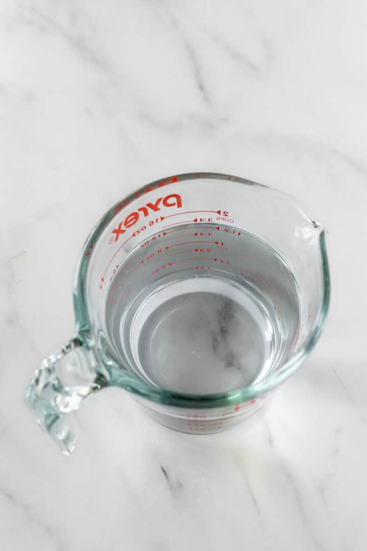 water in a liquid measuring cup on a white counter.