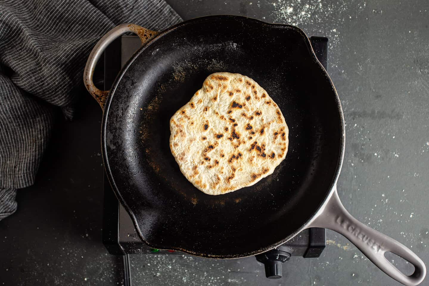 Cooking homemade pita bread on an enameled cast iron skillet.