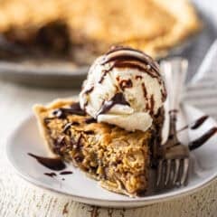 A thick slice of derby pie with a scoop of vanilla ice cream and chocolate syrup.
