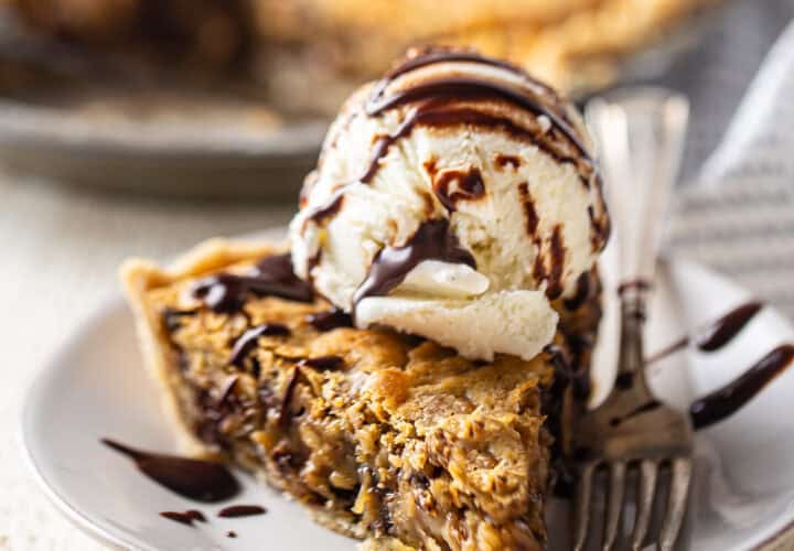 A thick slice of derby pie with a scoop of vanilla ice cream and chocolate syrup.