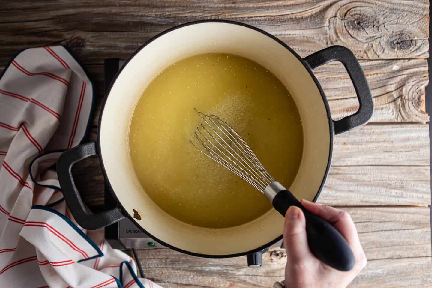 Whisking grits into boiling chicken stock.