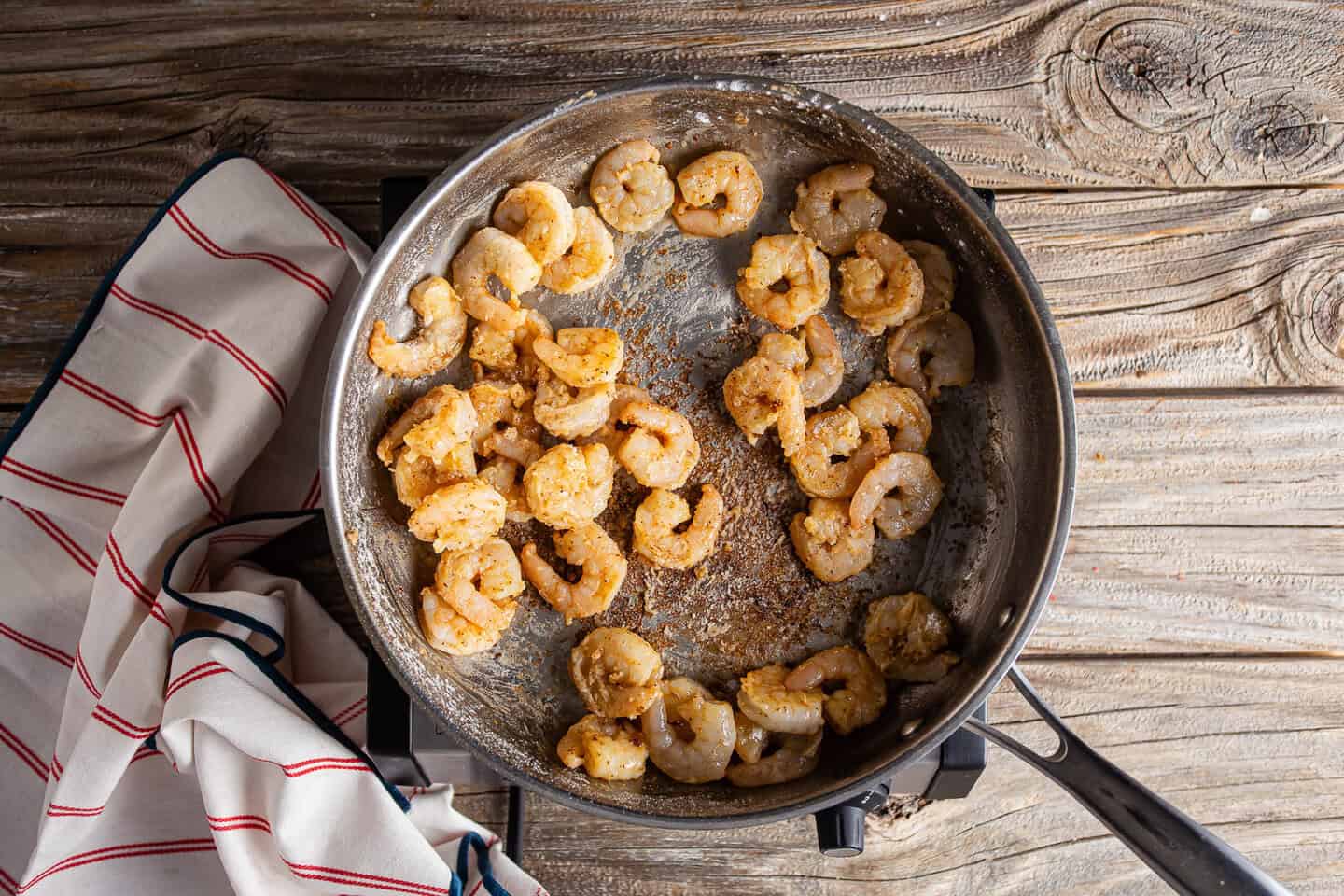 Sprinkling flour over searing shrimp to create a roux.
