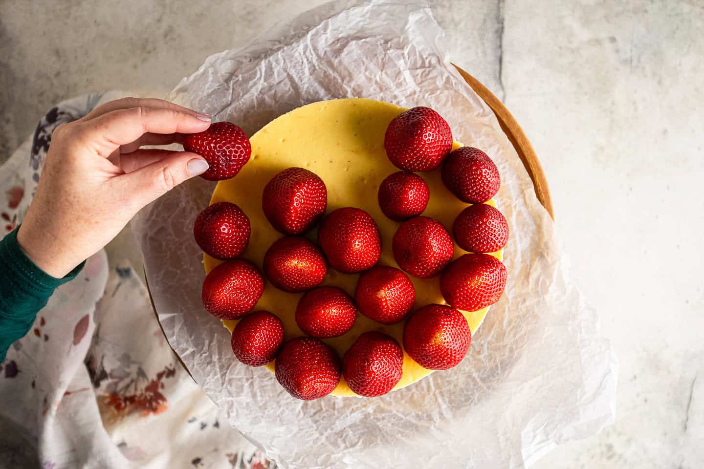 Placing fresh strawberries on a cheesecake.