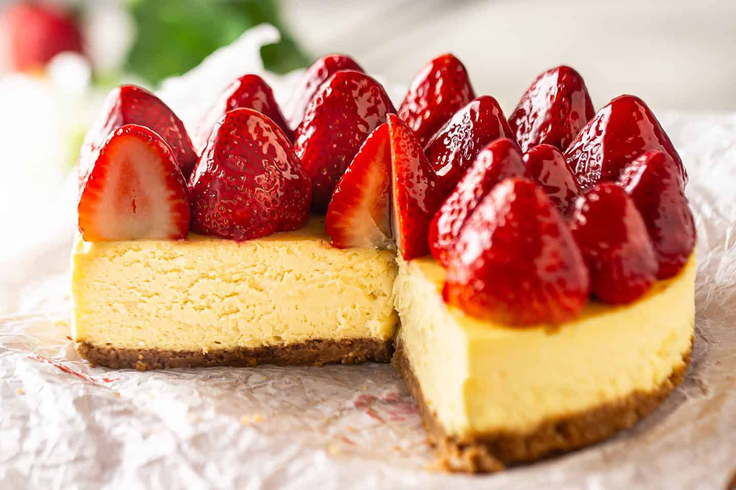 Strawberry cheesecake topping on a New York-style cheesecake with slices removed, displaying the creamy interior.