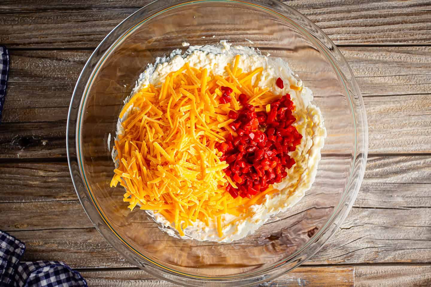 Adding shredded cheddar cheese and diced pimentos to base.