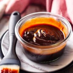 Barbecue sauce in a shallow glass dish with a basting brush.