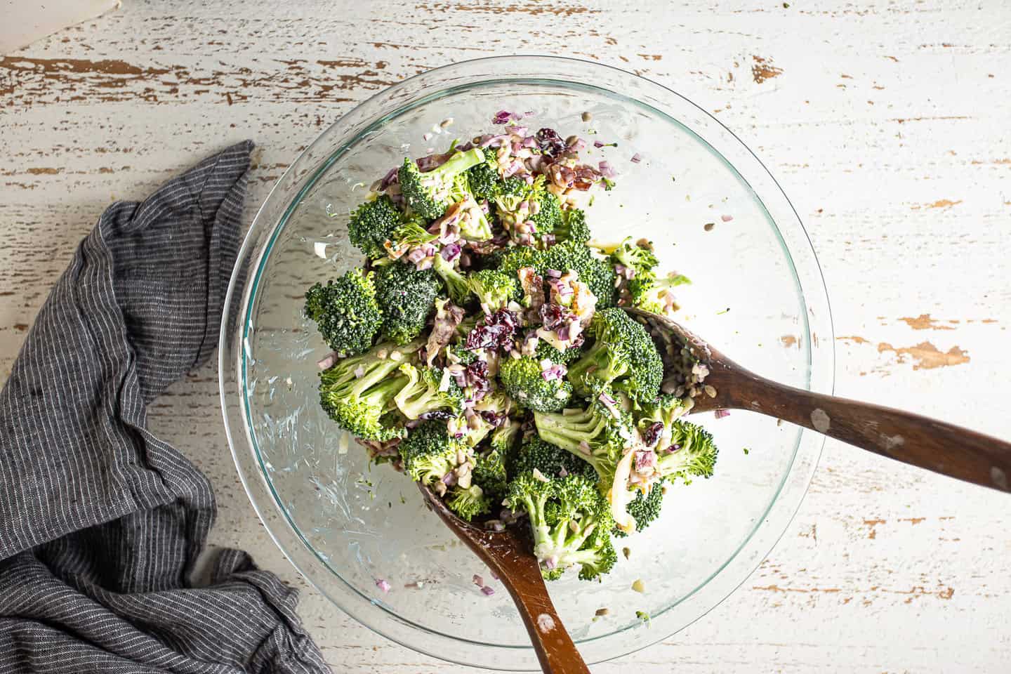 Tossing broccoli salad together to coat in dressing.