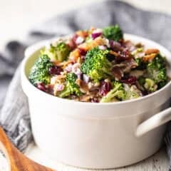 Broccoli salad in a white serving bowl with handles.