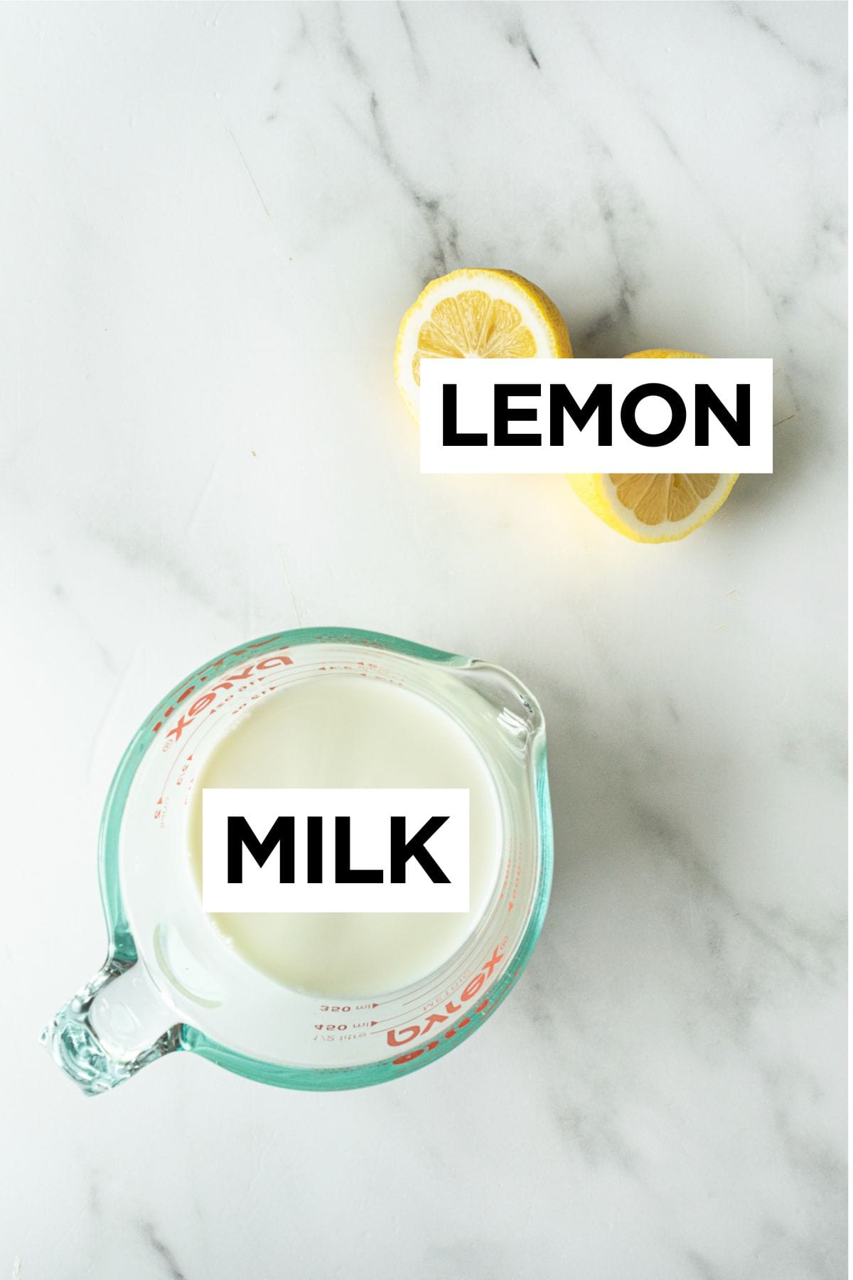 ingredients for how to make buttermilk such as whole milk and lemon on a white table.