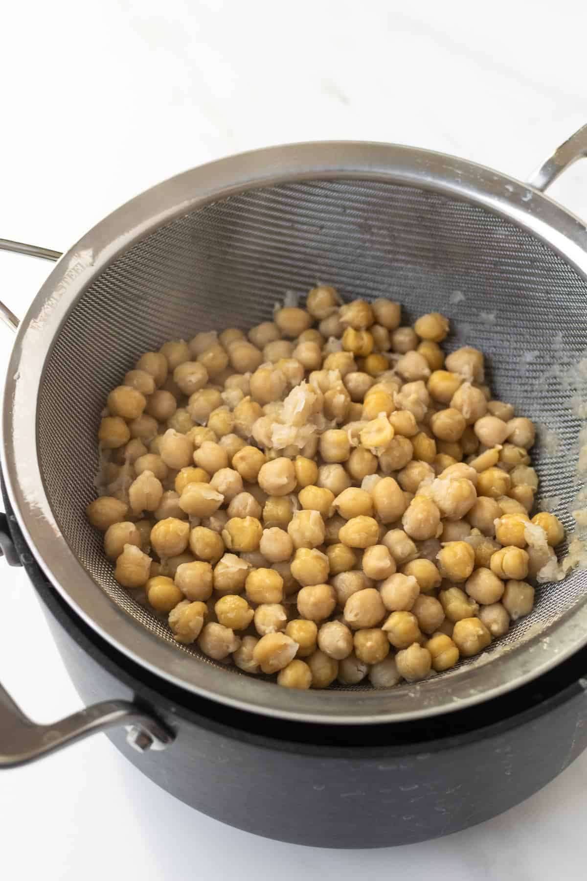 boiled chickpeas in a strainer sitting in a black pot.