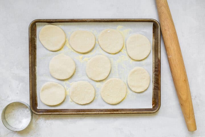 English muffin dough that has been rolled out and cut into rounds.