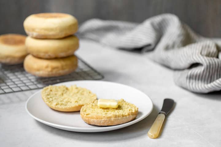 Homemade English muffins on a plate with butter.