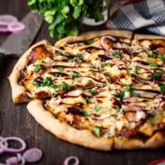 A homemade barbecue chicken pizza, sprinkled with cilantro leaves.