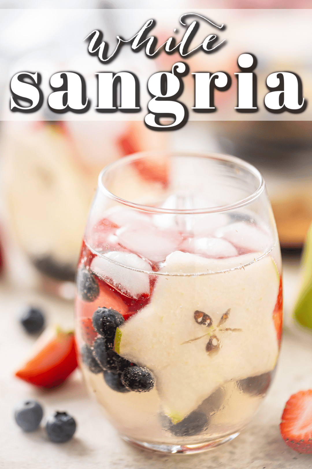 White sangria in a glass with strawberries, blueberries, and pear.
