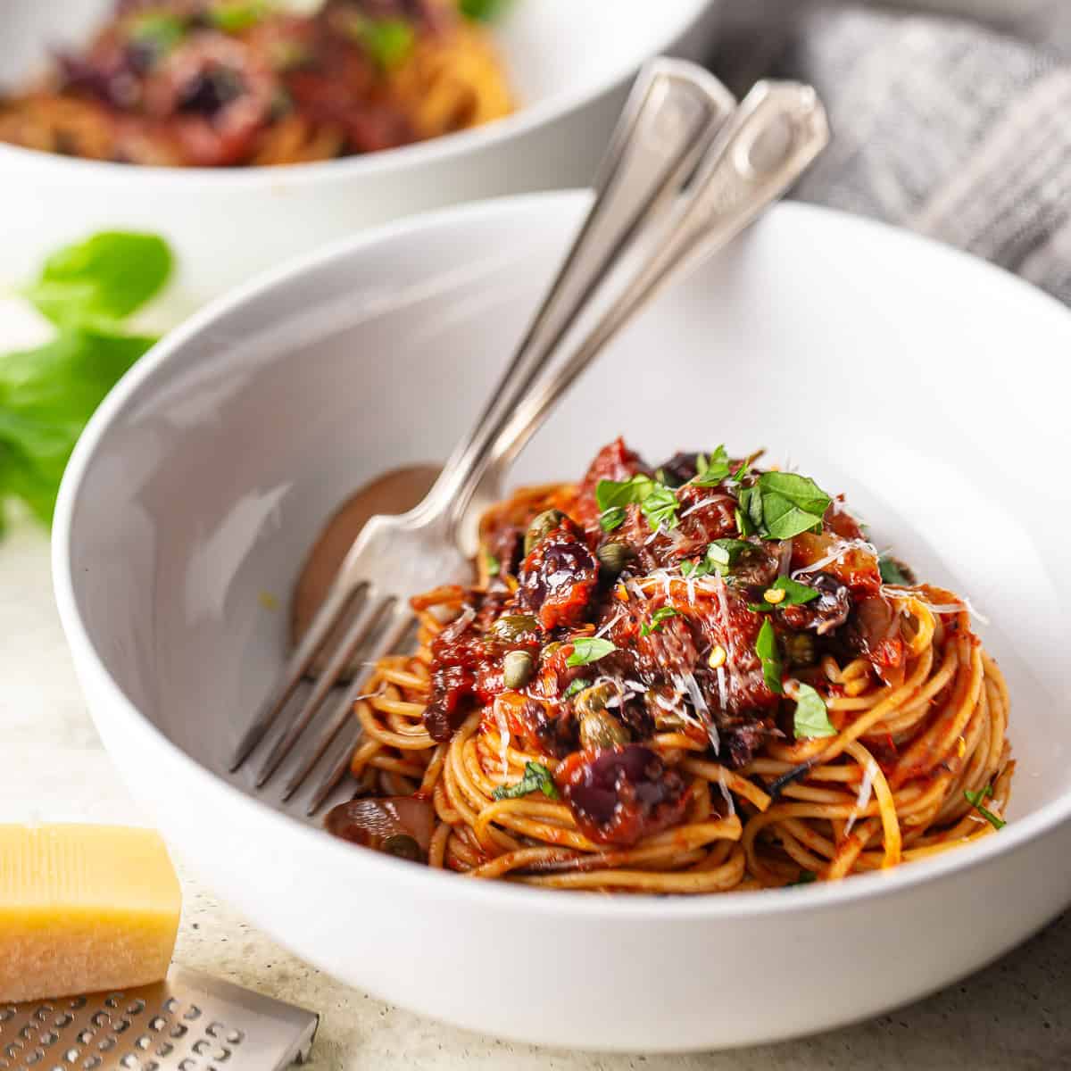Spaghetti alla puttanesca nestled into a white ceramic bowl.