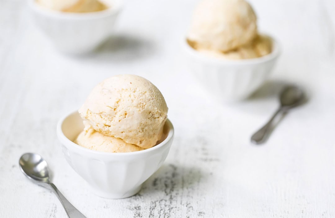 Peach ice cream in 3 bowls with spoons