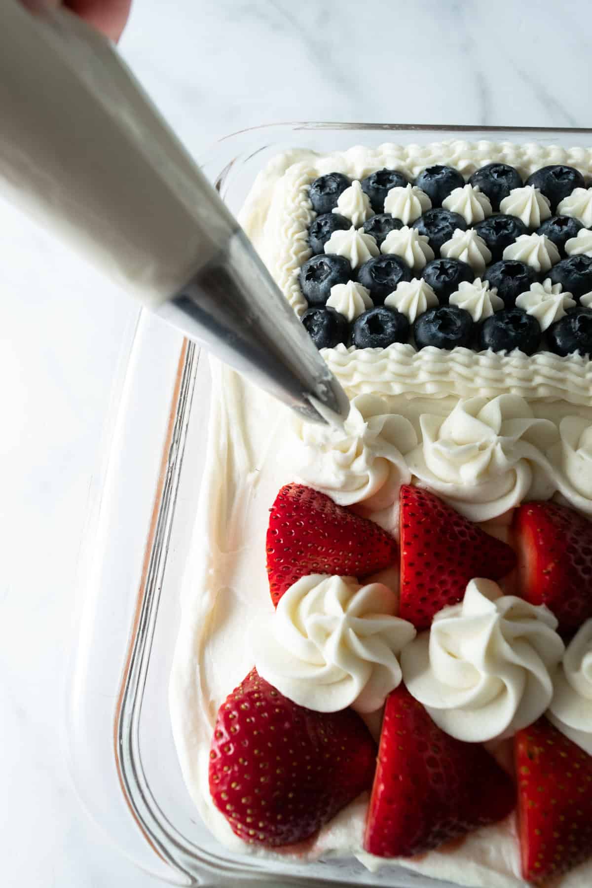 piping stripes onto American flag cake with piping bag.