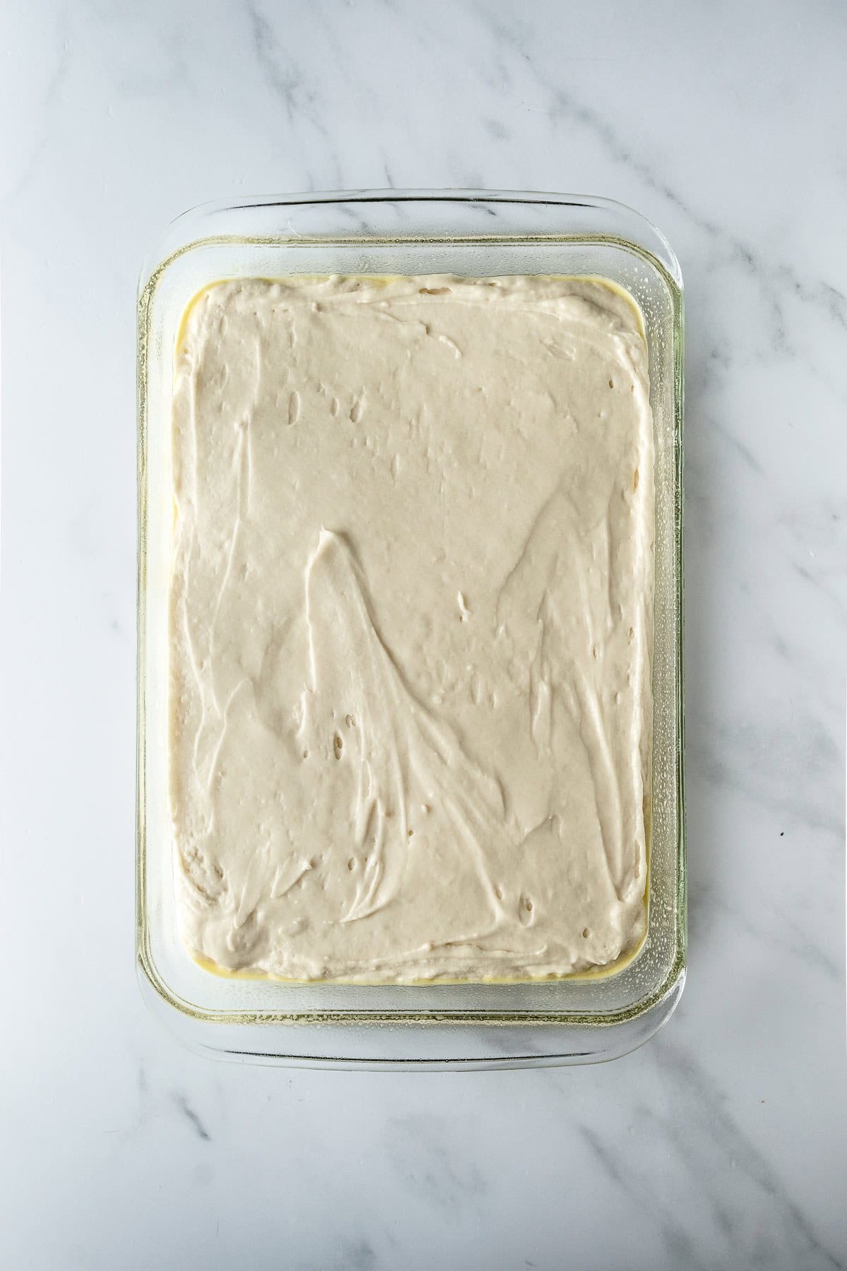 batter for vanilla cake in a baking dish on a white table.