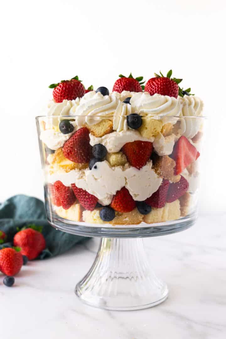 no-bake cheesecake berry trifle in a bowl with cake and berries.