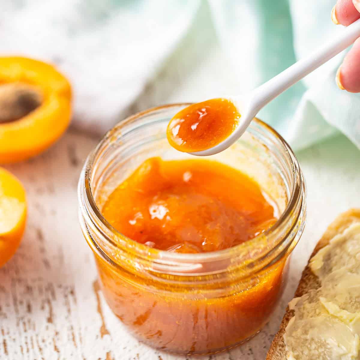 Spooning apricot jam from a glass jar.