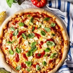 Overhead image of corn pizza with basil, tomato sauce, and Boursin cheese.