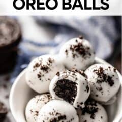 oreo balls in a white bowl with a bite taken from one.