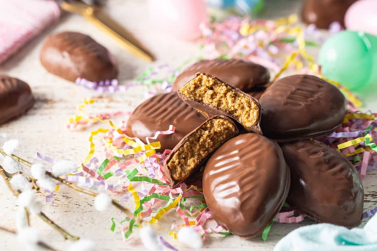 Peanut butter eggs recipe prepared and piled on a bed of pastel-colored Easter grass.