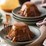 Individual sticky toffee pudding cakes on green plates.