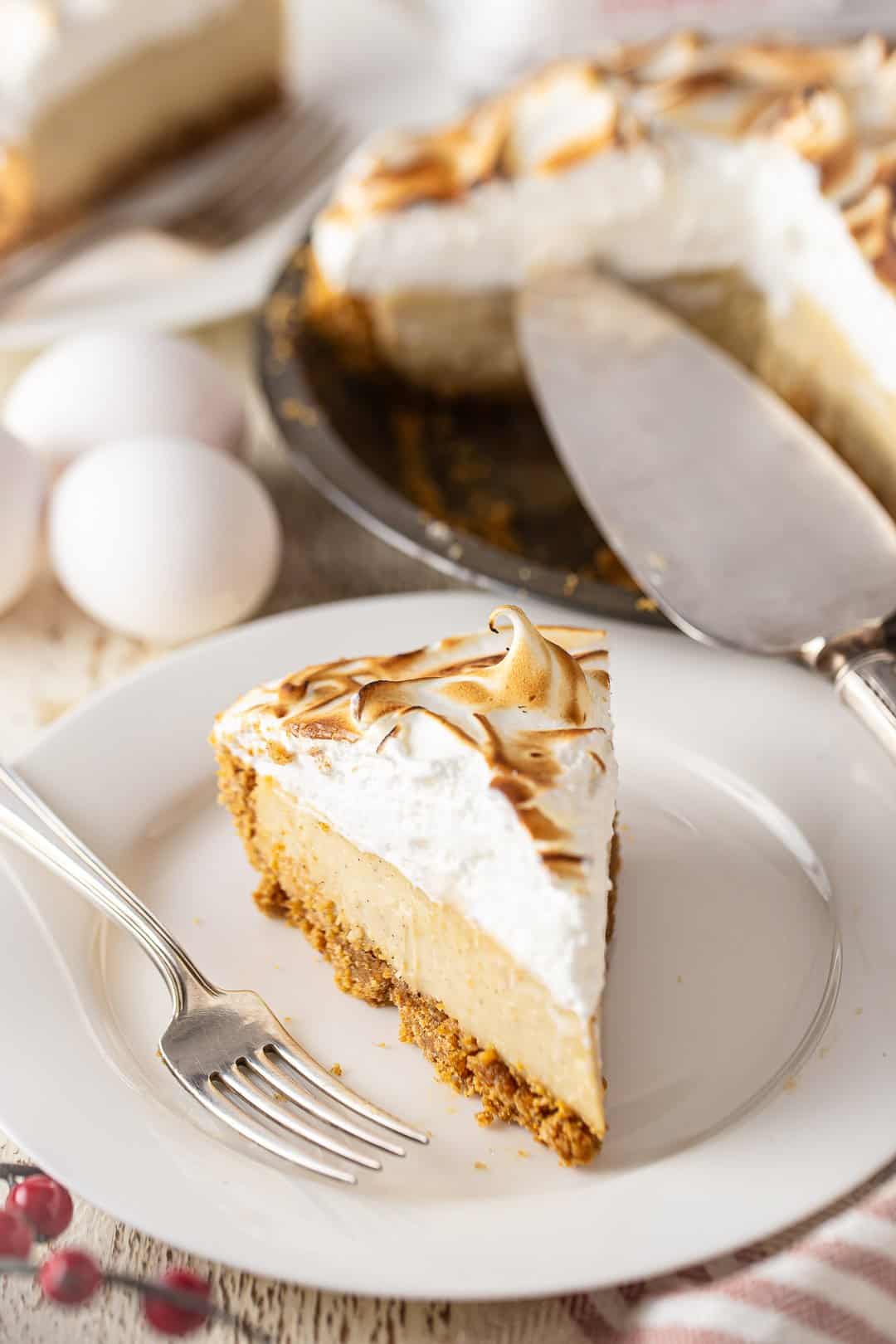 Homemade eggnog pie on a white plate with a pie server pictured behind it.