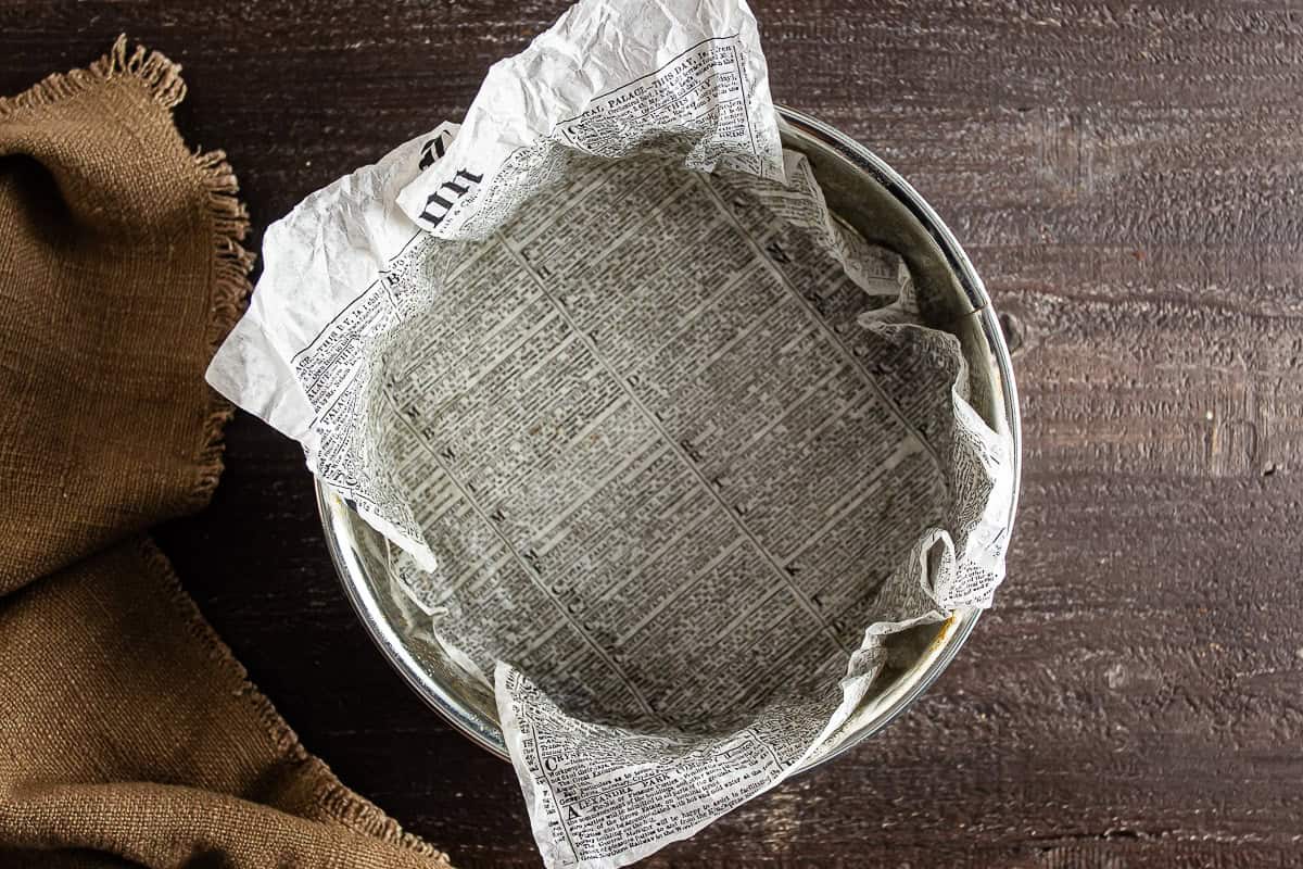 Parchment paper lining a springform pan for Basque cheesecake.