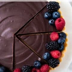 cut slices of chocolate tart on a cake stand with fresh berries on some slices with text overlay