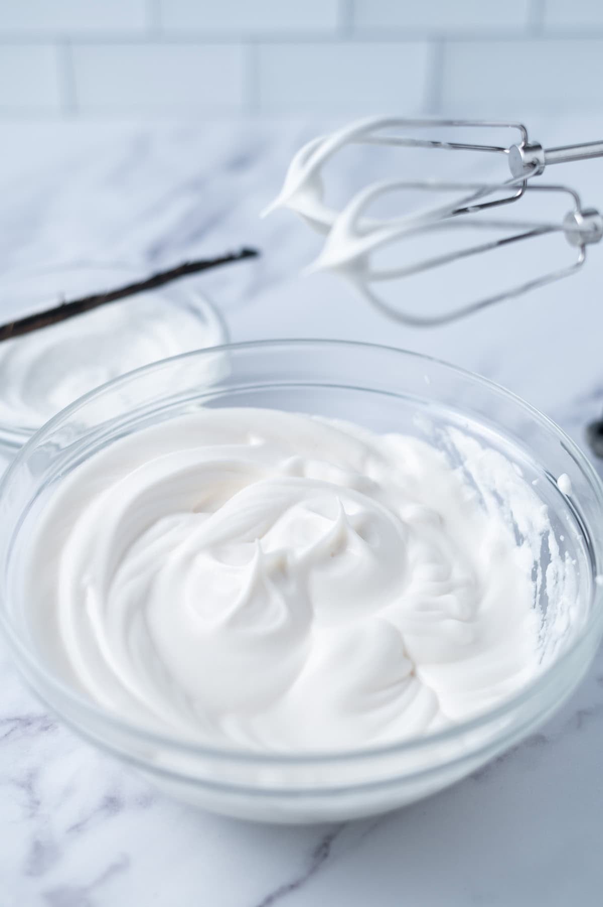 whipped egg whites in a glass bowl with a hand mixer