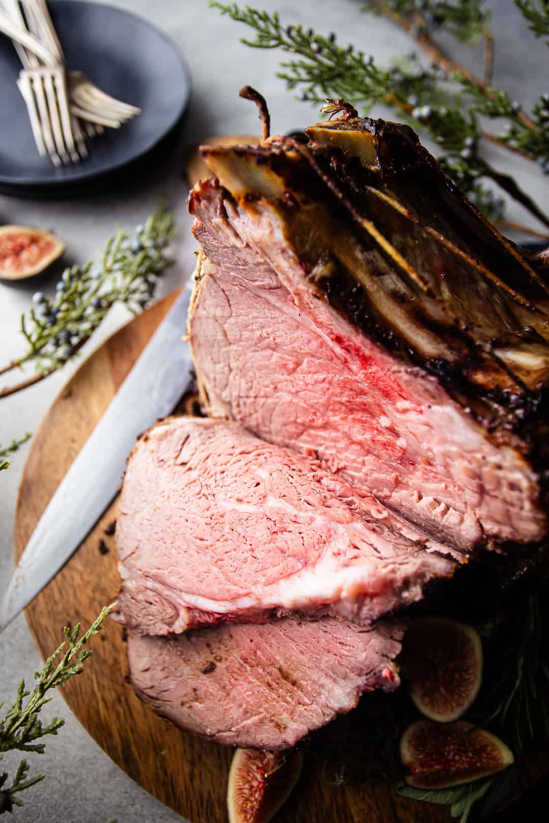 Standing rib roast with slices cut from it on a wooden cutting board.