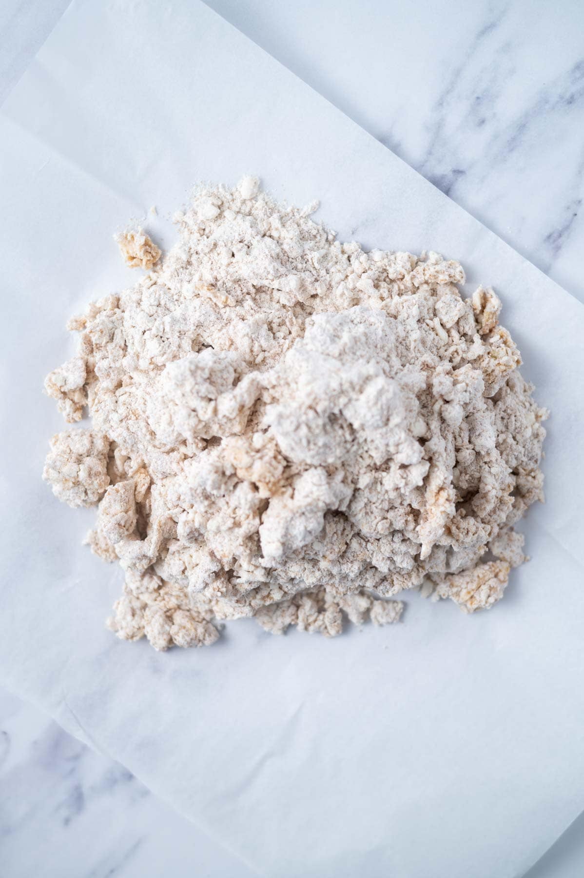 crumbly scone dough on a sheet of parchment paper