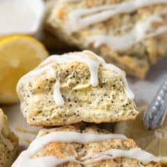 scone with glaze dripping down leaning on other scones with lemon slices in the background