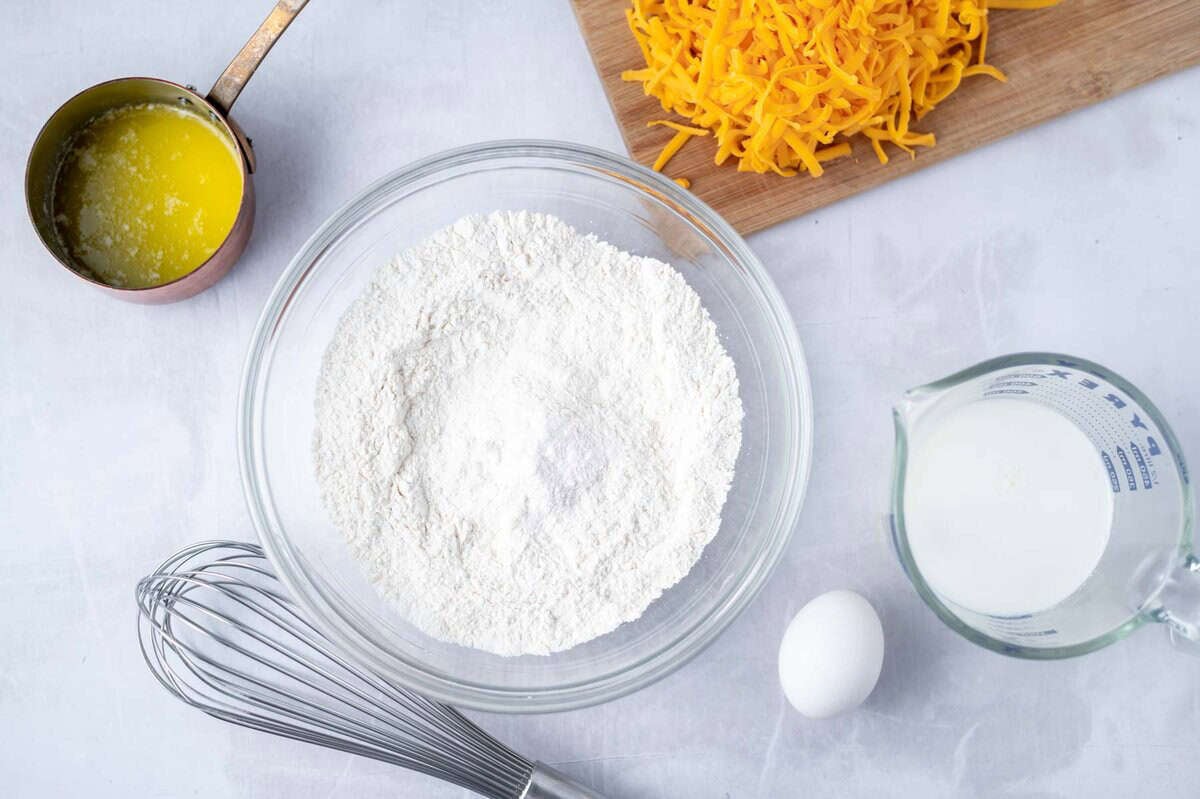 dry ingredients whisked together in a bowl with melted butter, cheese, egg and milk on the side