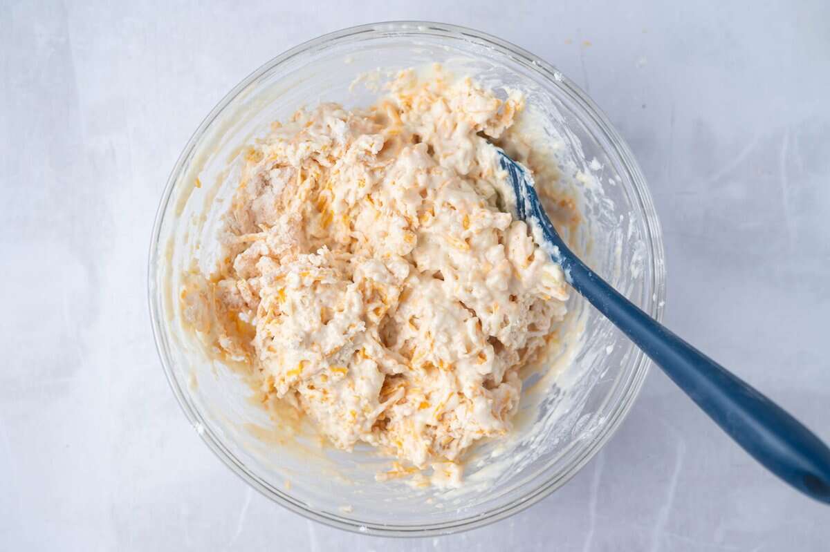 cheese bread batter in a glass mixing bowl with a spatula