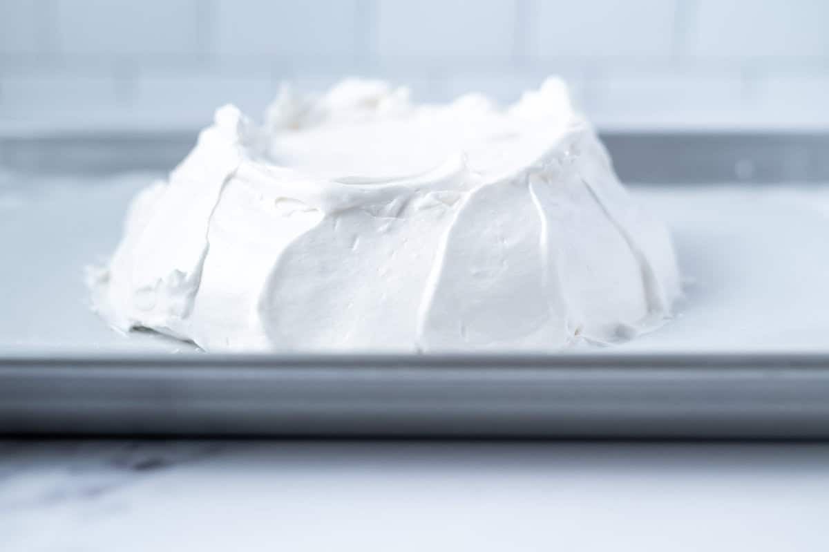 swooping shaped sides of unbaked pavlova on a baking pan