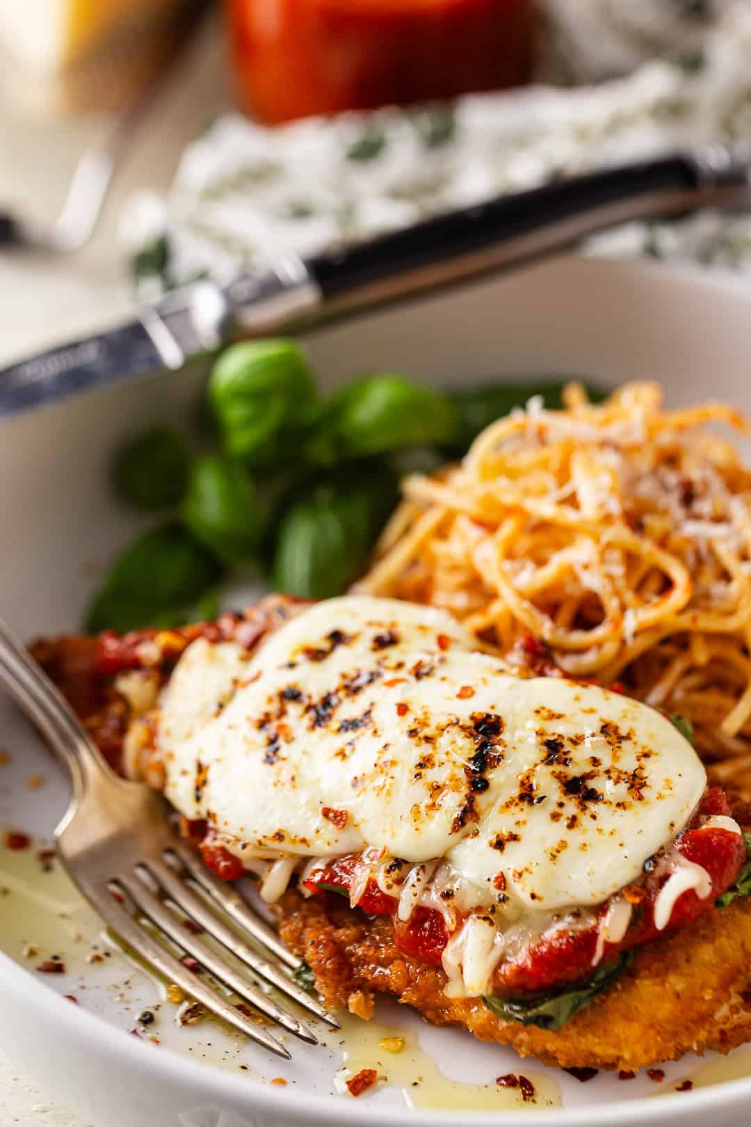 Chicken parmesan with pasta and fresh basil.