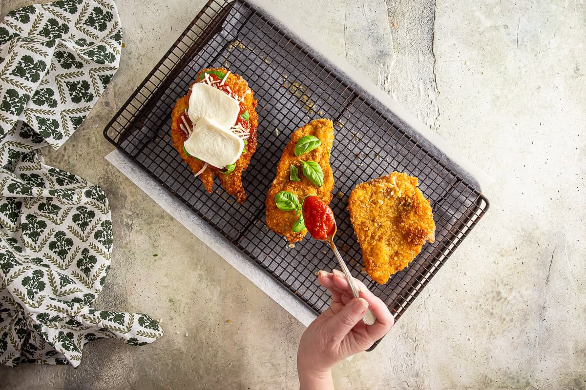 Basil, sauce, and cheese added to chicken parmesan.